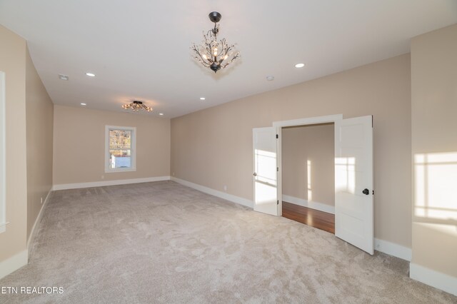 carpeted empty room featuring a chandelier