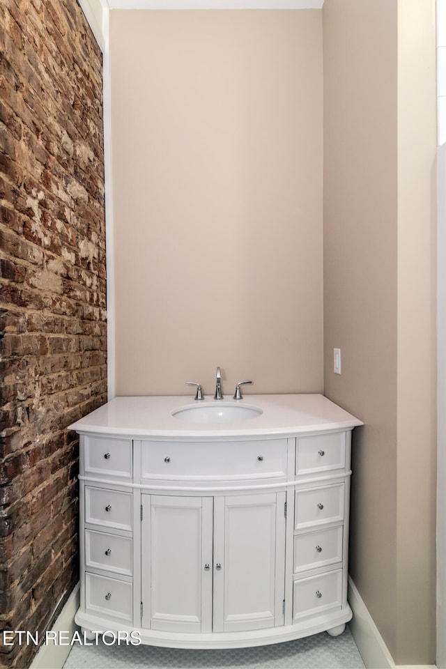 bathroom featuring vanity and brick wall