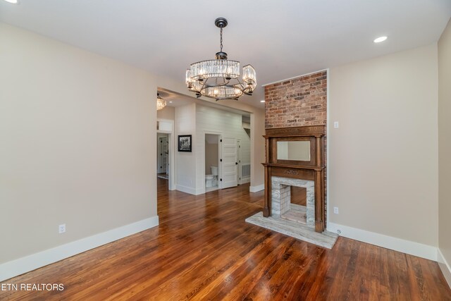 unfurnished living room with dark wood-type flooring, a notable chandelier, and a fireplace