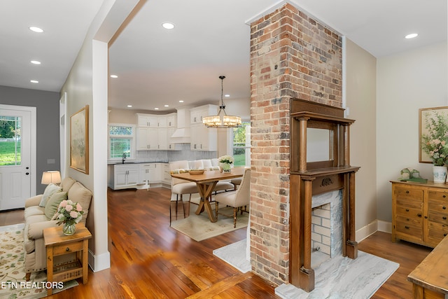 dining room with dark hardwood / wood-style flooring, a chandelier, sink, and a brick fireplace