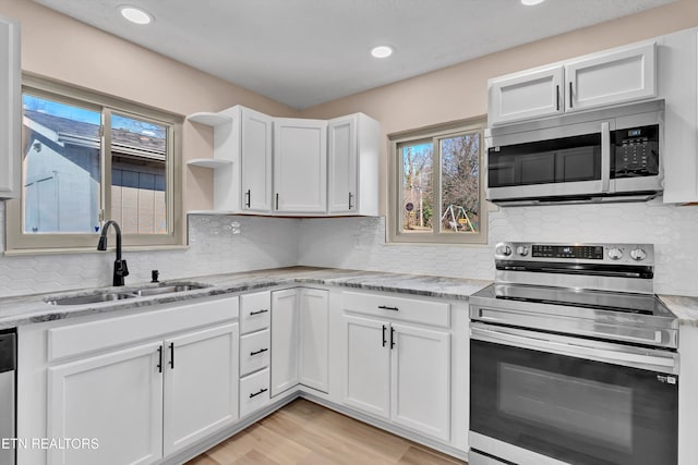 kitchen with white cabinets, stainless steel appliances, light stone counters, and sink