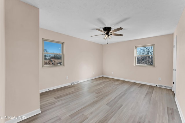 empty room with a textured ceiling, light hardwood / wood-style floors, and ceiling fan