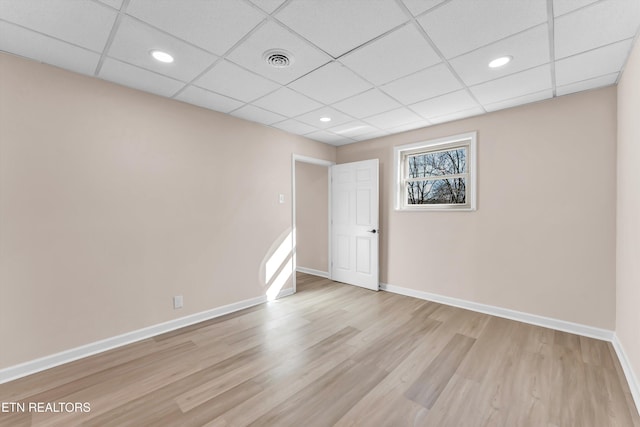 spare room with a drop ceiling and light wood-type flooring