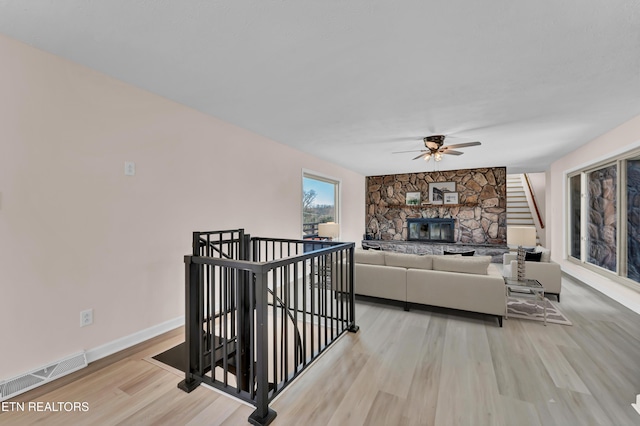 living room featuring ceiling fan, light wood-type flooring, and a fireplace