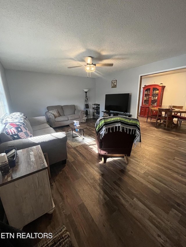 living room featuring dark hardwood / wood-style flooring, a textured ceiling, and ceiling fan