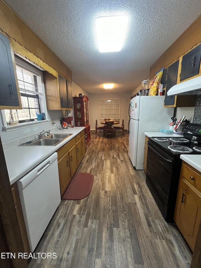 kitchen with a textured ceiling, white appliances, dark hardwood / wood-style floors, and sink