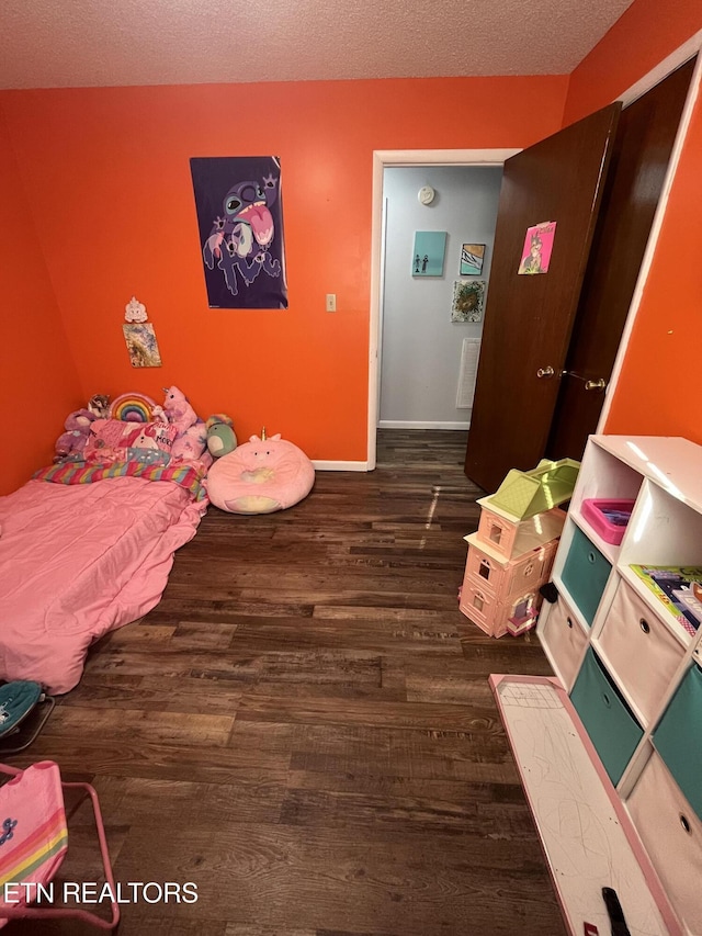 bedroom featuring dark hardwood / wood-style flooring and a textured ceiling