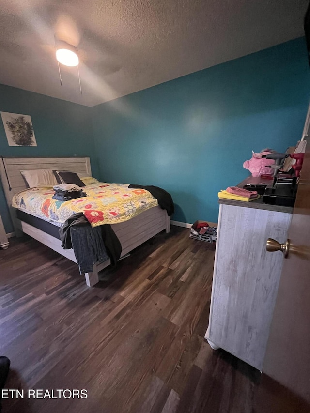 bedroom with ceiling fan, dark hardwood / wood-style flooring, and a textured ceiling