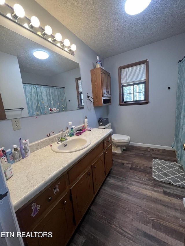 bathroom featuring toilet, vanity, a textured ceiling, and hardwood / wood-style flooring