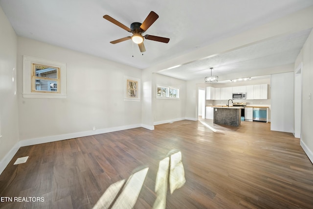 unfurnished living room with ceiling fan, wood-type flooring, and sink