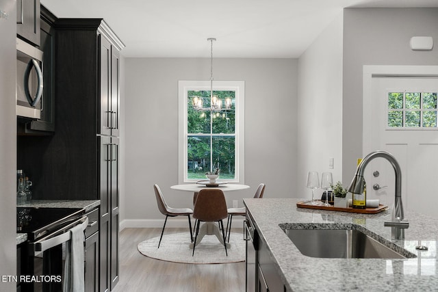 kitchen with appliances with stainless steel finishes, light stone countertops, sink, and a wealth of natural light