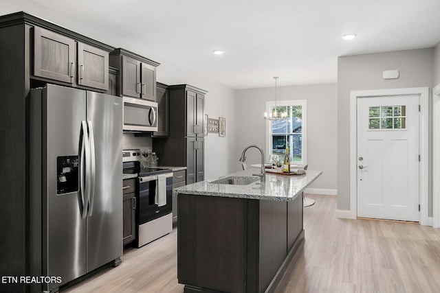 kitchen featuring stainless steel appliances, light hardwood / wood-style flooring, a notable chandelier, and sink