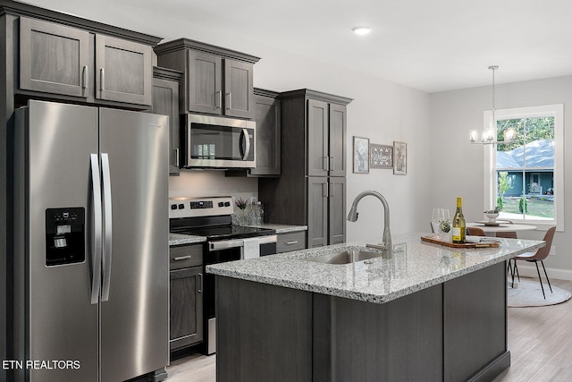 kitchen featuring light stone countertops, sink, stainless steel appliances, and light hardwood / wood-style floors