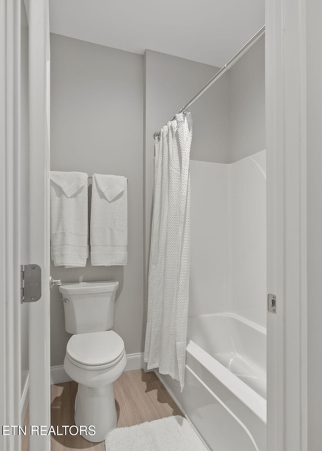 bathroom featuring hardwood / wood-style flooring, toilet, and shower / bath combo with shower curtain