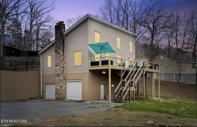 1448 Dover Ln, Dandridge, TN 37725 - back of house at dusk featuring an attached garage, stairway, a chimney, gravel driveway, and a deck