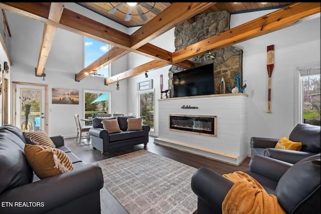 living room with hardwood / wood-style floors, high vaulted ceiling, a stone fireplace, ceiling fan, and beam ceiling