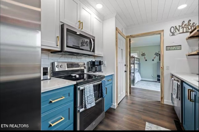 kitchen with dark hardwood / wood-style floors, blue cabinets, backsplash, white cabinets, and appliances with stainless steel finishes