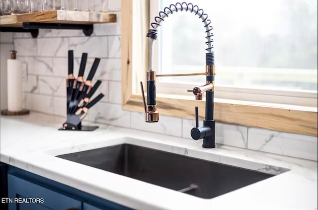 interior details featuring tasteful backsplash, blue cabinets, and sink