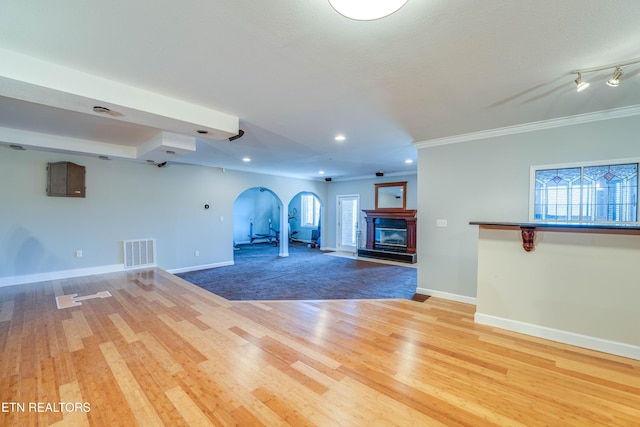 unfurnished living room featuring ornamental molding, a healthy amount of sunlight, and wood-type flooring