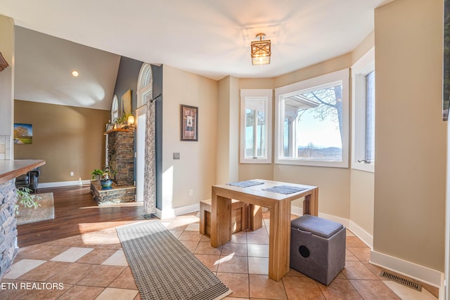 dining space with a fireplace, light hardwood / wood-style floors, and lofted ceiling