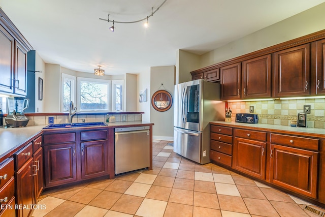 kitchen featuring tasteful backsplash, sink, light tile patterned floors, and appliances with stainless steel finishes