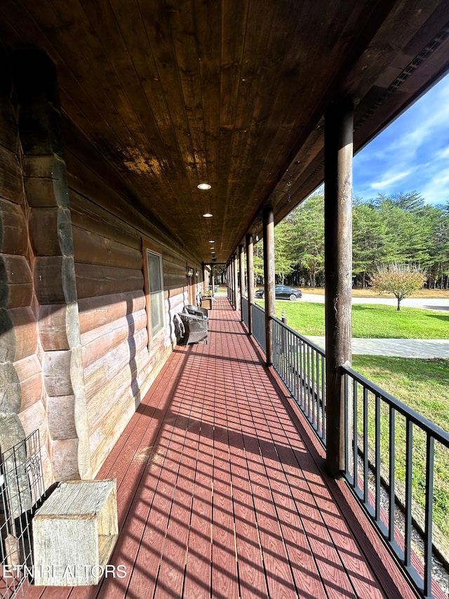 wooden terrace with covered porch and a lawn