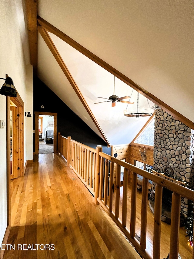 corridor with wooden walls, high vaulted ceiling, and hardwood / wood-style flooring