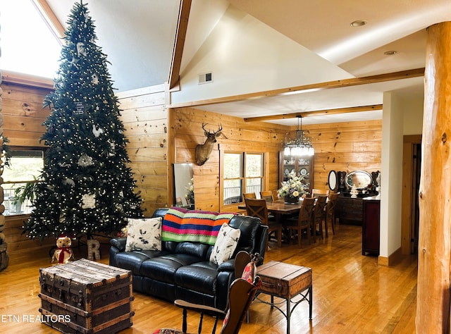 living room with beam ceiling, light wood-type flooring, high vaulted ceiling, and wood walls