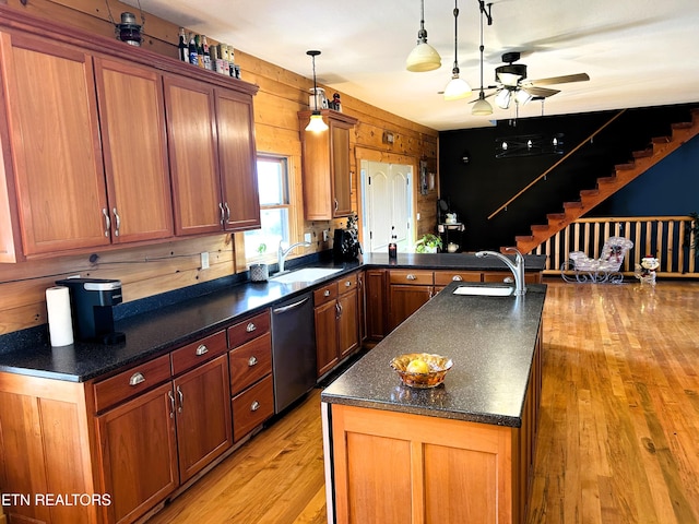 kitchen featuring wooden walls, sink, stainless steel dishwasher, and light hardwood / wood-style flooring