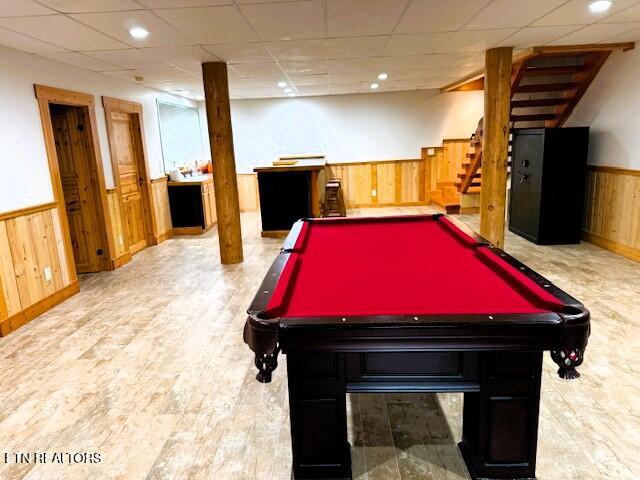 recreation room featuring wooden walls, a drop ceiling, billiards, and light hardwood / wood-style flooring