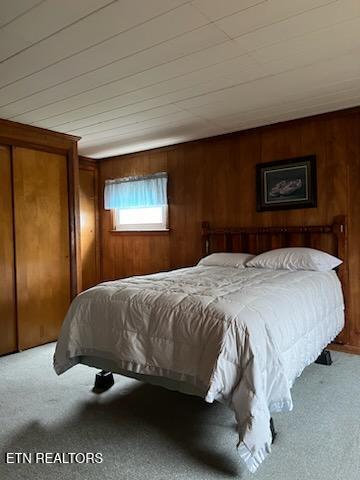 bedroom with wooden walls and carpet