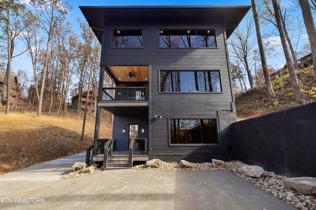 rear view of property with a balcony and ceiling fan