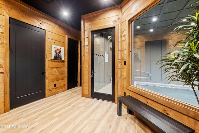 interior space featuring light wood-type flooring and wooden walls