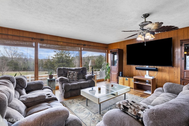 living area with a textured ceiling, wood walls, and light wood-style floors