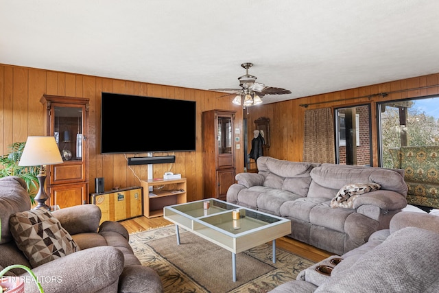 living area with light wood-type flooring, ceiling fan, and wood walls