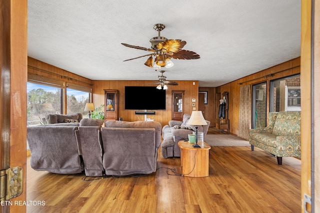 living room featuring wooden walls, a textured ceiling, and wood finished floors