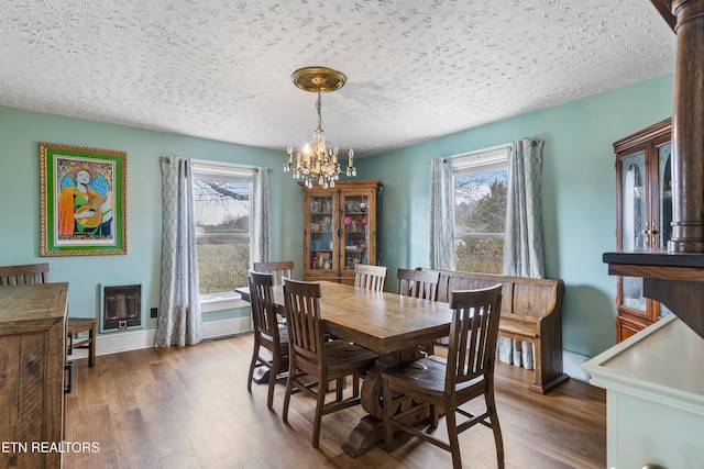 dining space with a chandelier, dark wood-type flooring, a textured ceiling, and a healthy amount of sunlight