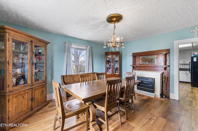 dining area featuring a glass covered fireplace, a notable chandelier, light wood-style flooring, and heating unit