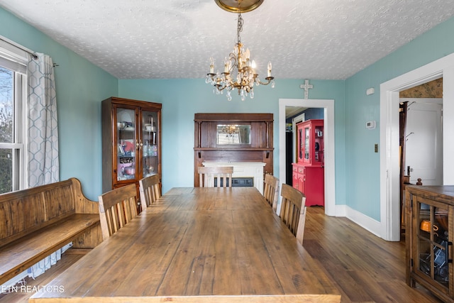 dining room with a textured ceiling, baseboards, dark wood finished floors, and a chandelier