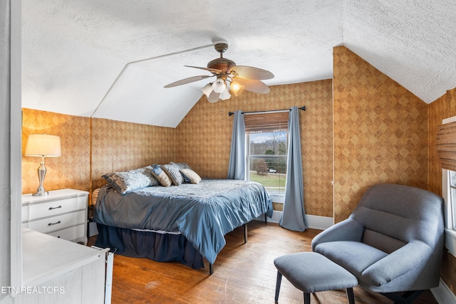 bedroom featuring vaulted ceiling, a textured ceiling, and light wood-type flooring