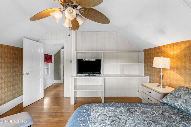 bedroom with lofted ceiling, ceiling fan, baseboards, dark wood finished floors, and wallpapered walls