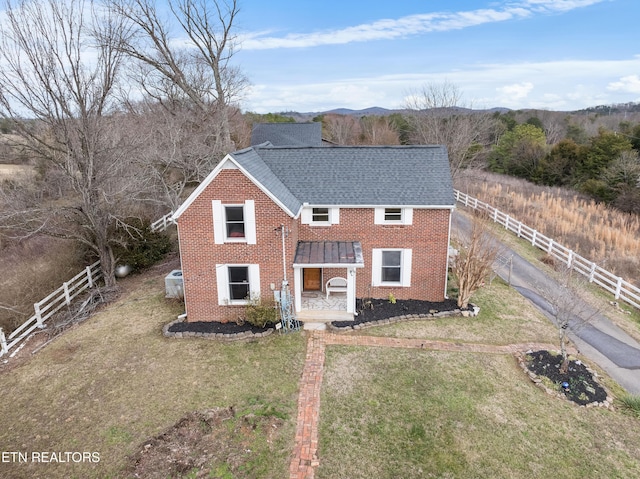 view of front of home with a shingled roof, brick siding, fence, and a front lawn