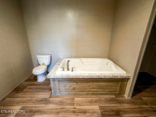 bathroom with hardwood / wood-style floors, a bath, and toilet