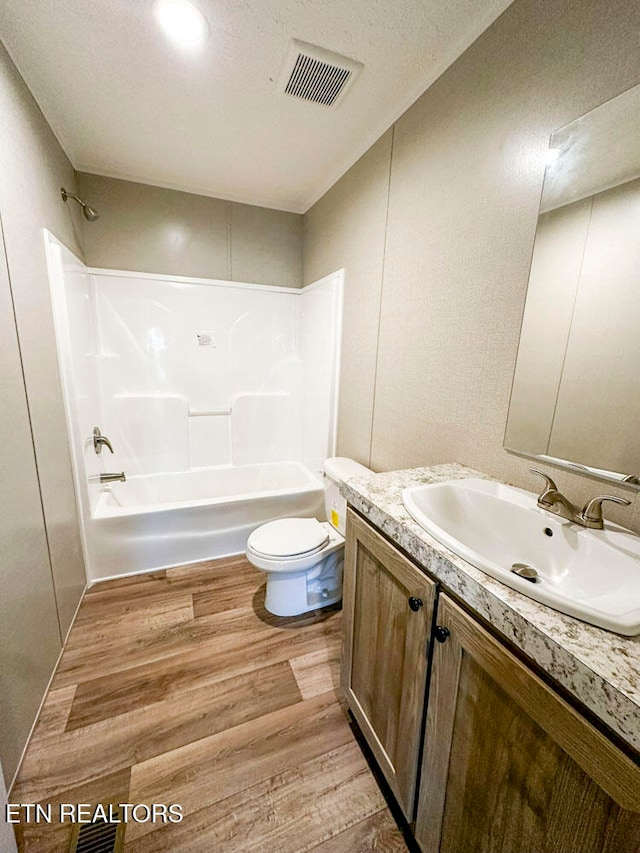 full bathroom with toilet, hardwood / wood-style floors, vanity, and washtub / shower combination