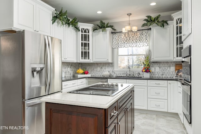 kitchen featuring white cabinets, stainless steel fridge, crown molding, and sink