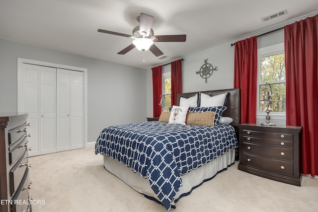 bedroom with a closet, light colored carpet, multiple windows, and ceiling fan