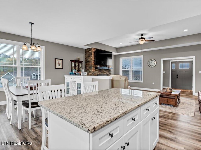 kitchen with white cabinets, pendant lighting, light hardwood / wood-style flooring, and a healthy amount of sunlight