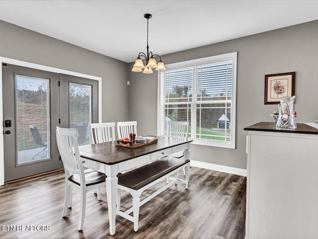 dining space with dark wood-type flooring and an inviting chandelier