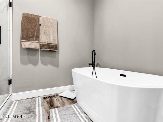 bathroom featuring hardwood / wood-style floors and independent shower and bath