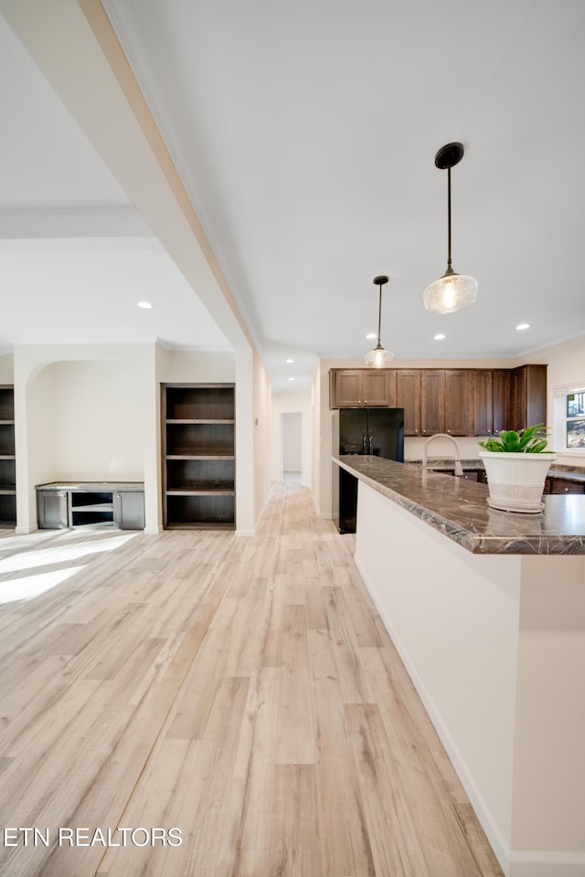 unfurnished living room featuring crown molding, sink, and light hardwood / wood-style floors